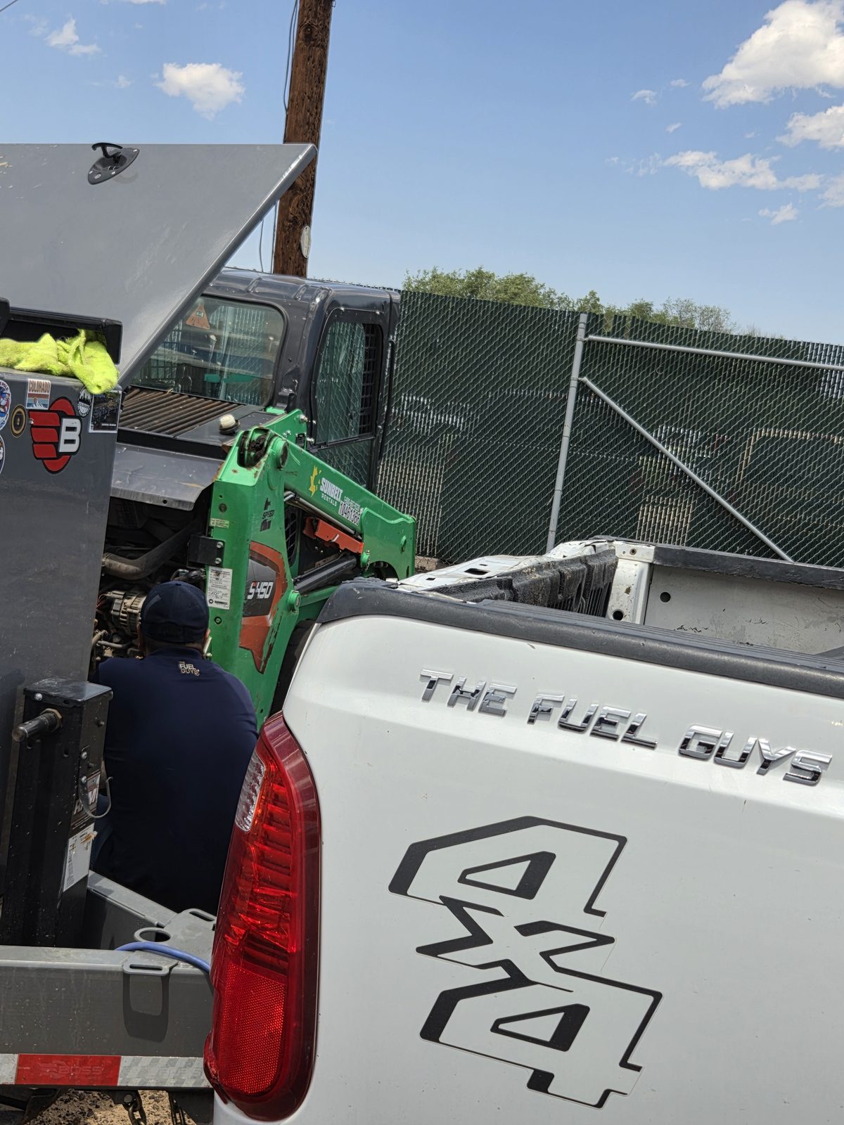 A Fuel Guys delivery truck fueling equipment on a Denver job site in summer.