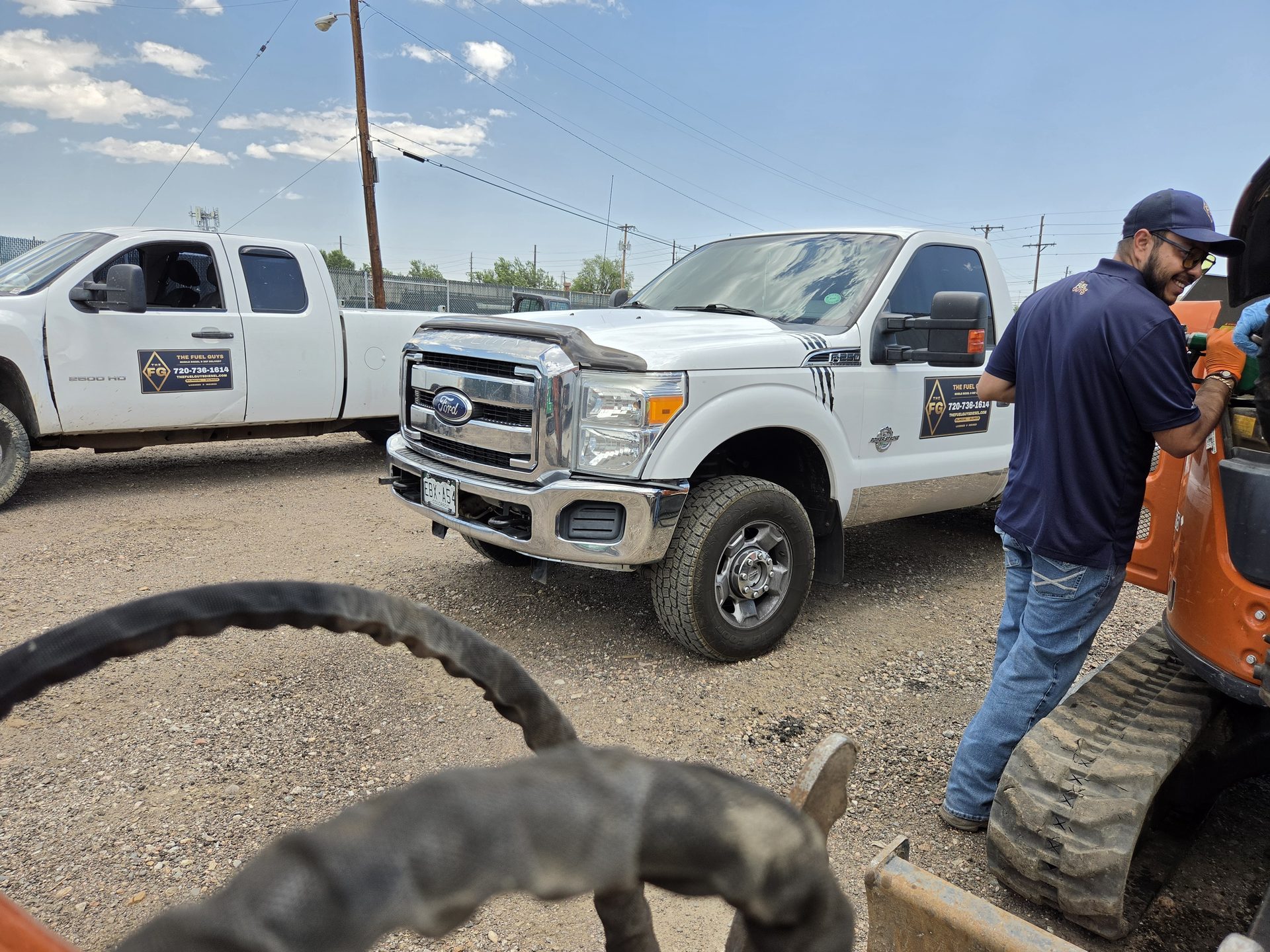The Fuel Guys branded trucks and uniformed driver fueling equipment on a Denver construction site
