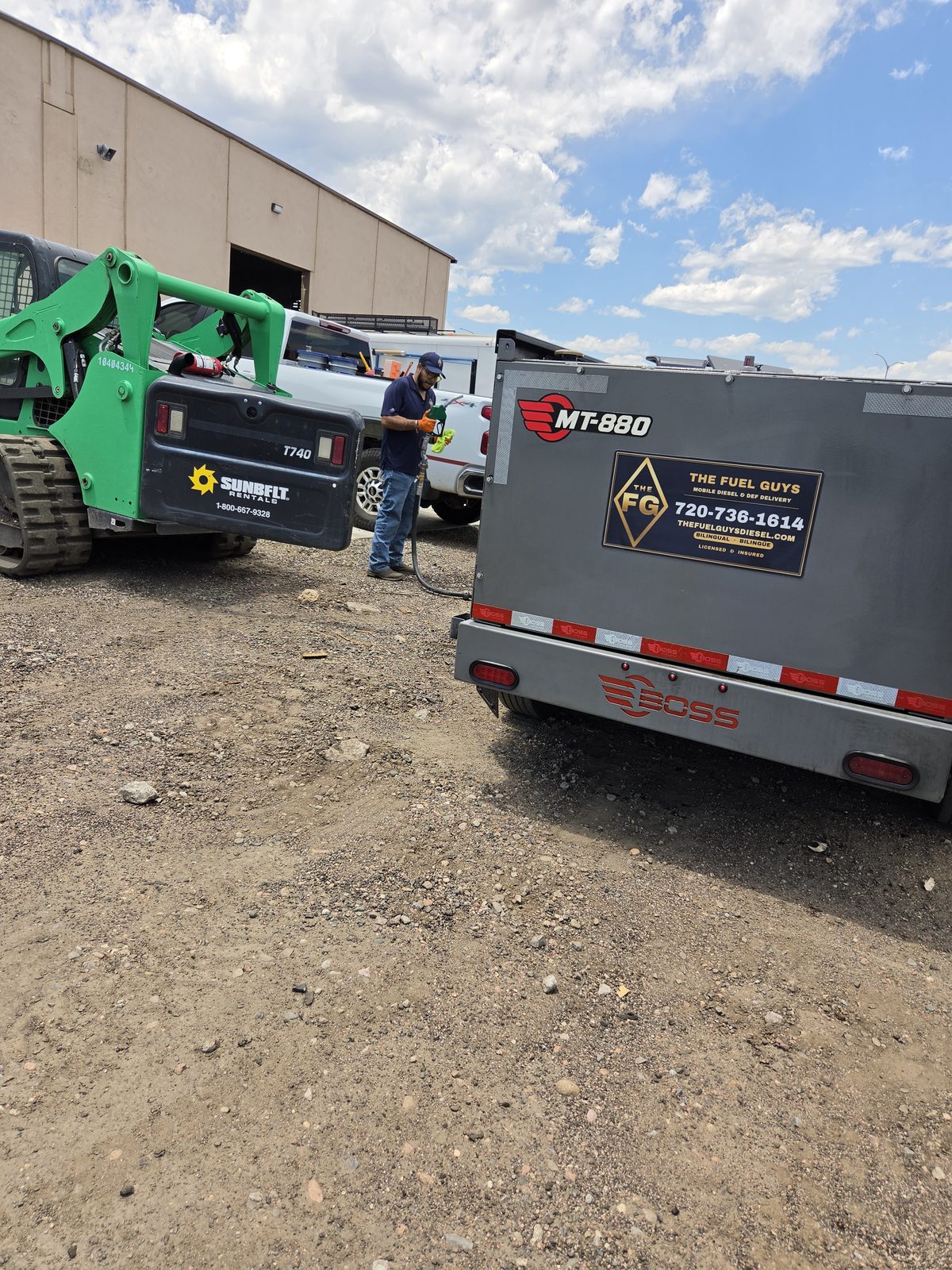 The Fuel Guys driver fueling equipment beside the branded fuel trailer
