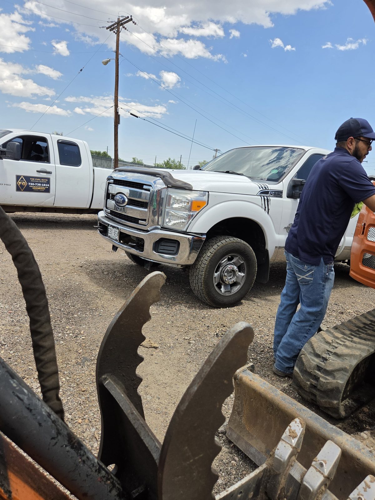 The Fuel Guys driver in uniform beside a branded delivery truck on a construction site